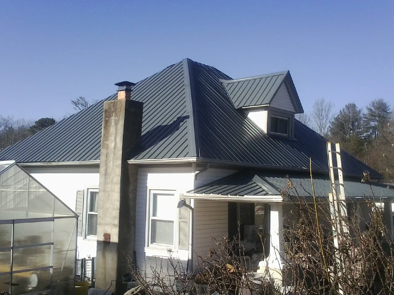 Dark blue standing seam metal roof on a white farmhouse with dormer — Slate & Tile Roof Repair by Roofing Brothers in Horse Cave