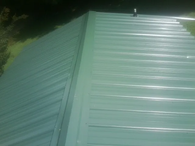 New green metal panels meeting at the ridge of a roof — Flat Roof Repair work by our crew in Horse Cave