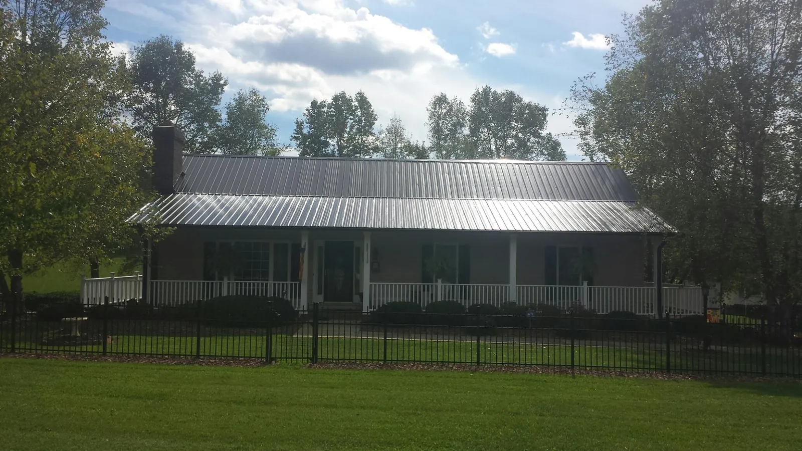 Gray metal roof on a brick ranch with a full width front porch — Gutter Guard Installation work by our crew in Horse Cave
