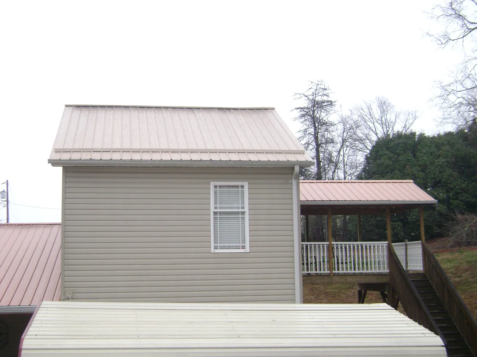 Tan metal roofs on a two story addition and attached porch, from a Roof Replacement job in Horse Cave