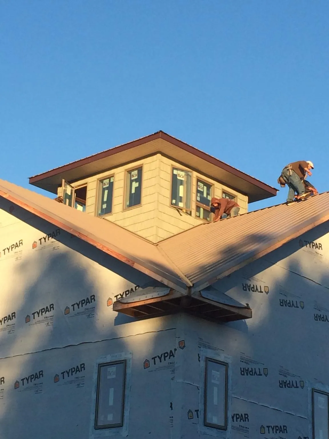 Roofers working around a rooftop cupola on a new metal roof at sunset — Roof Waterproofing in Horse Cave by Roofing Brothers